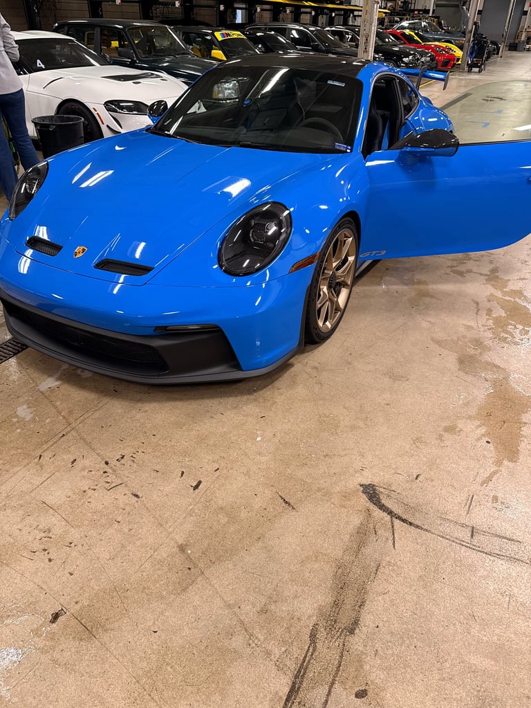 Bright blue sports car with open door in indoor parking garage with other vehicles in background