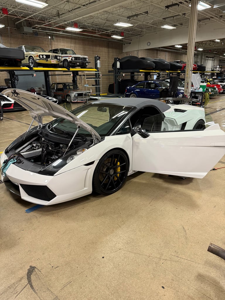 White sports car with open hood and door in automotive workshop, showcasing engine and luxury vehicle interior