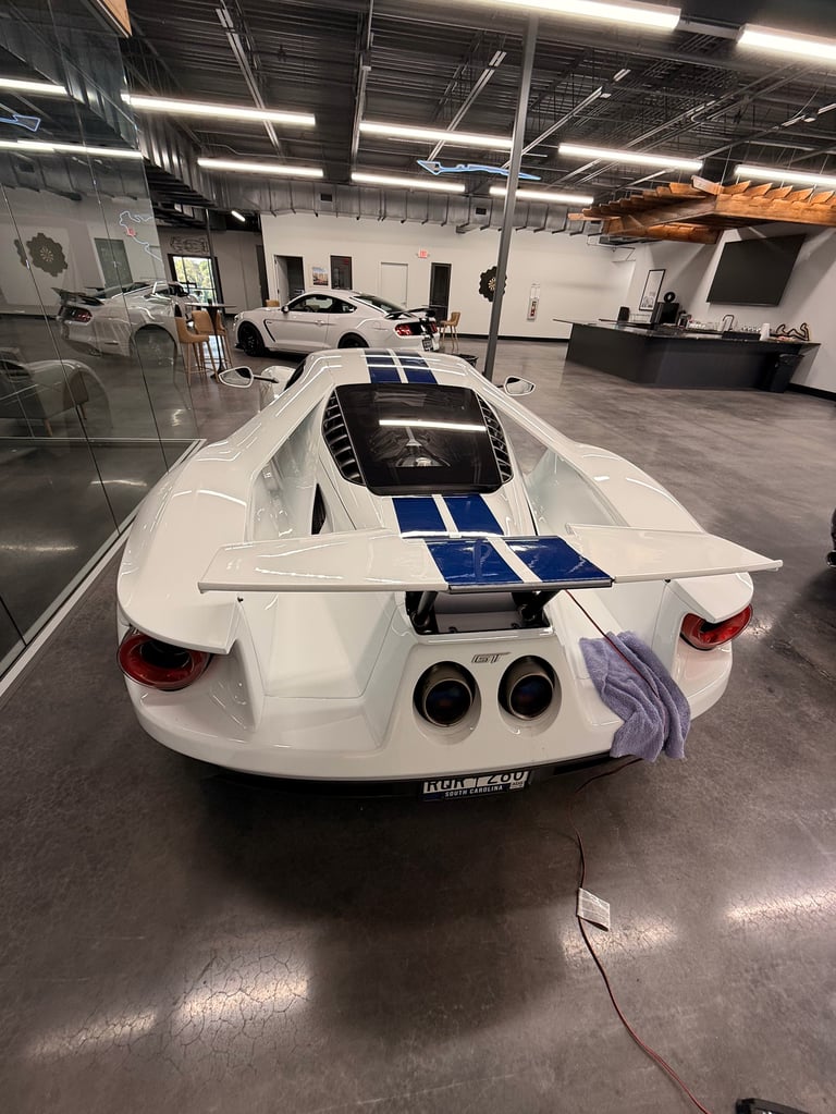 White sports car with blue racing stripes parked in a modern automotive showroom with polished concrete floor