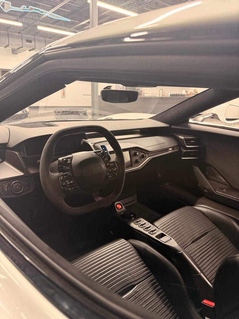 Interior view of a modern sports car with black steering wheel, dashboard, and ribbed gray seats in a showroom