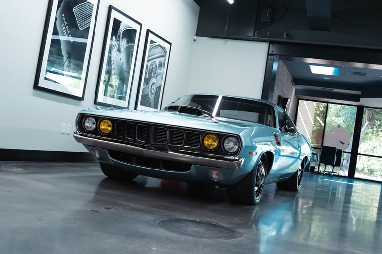Blue muscle car on display in modern showroom with framed artwork on white walls