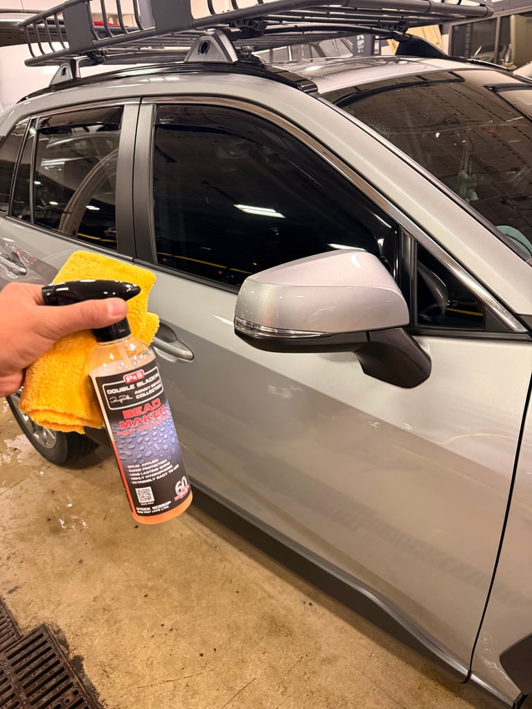 Person cleaning white SUV mirror with yellow microfiber cloth and spray bottle product