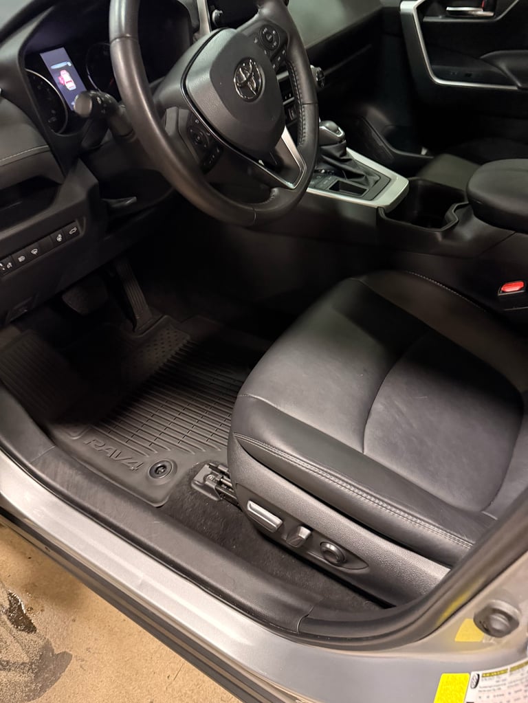 Interior view of Volkswagen vehicle showing steering wheel, dashboard, leather seats, and black floor mats