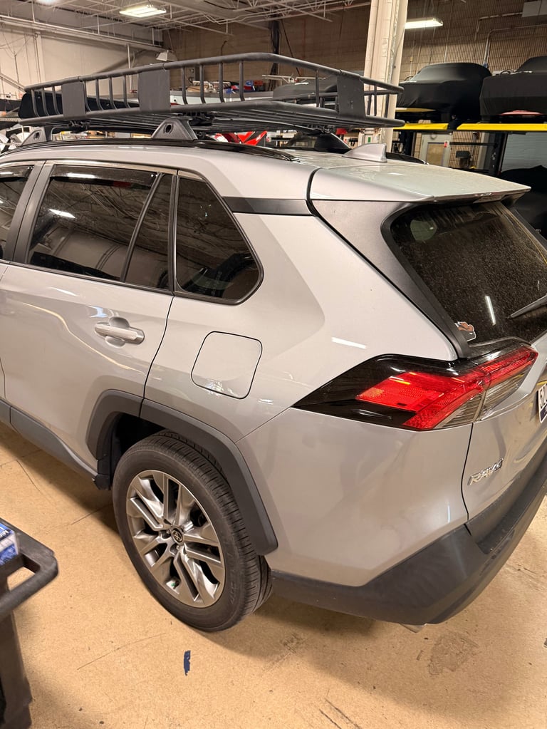 White SUV with roof rack and black roof cage in auto service garage