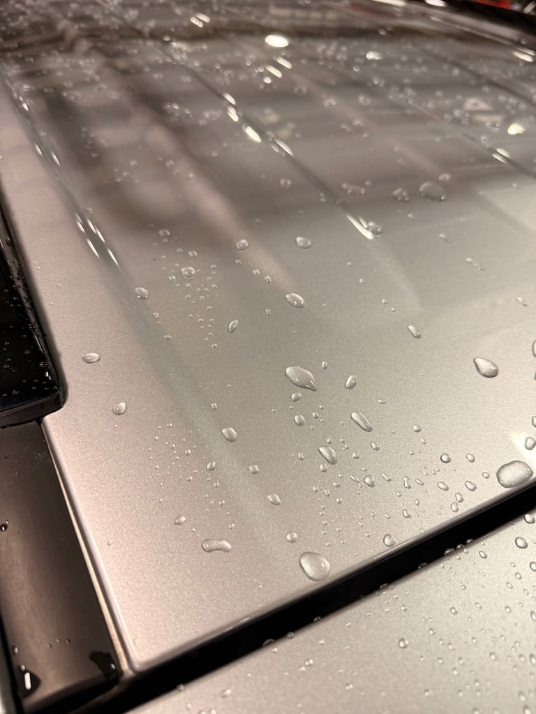 Water droplets on silver laptop lid with beaded condensation and reflective surface