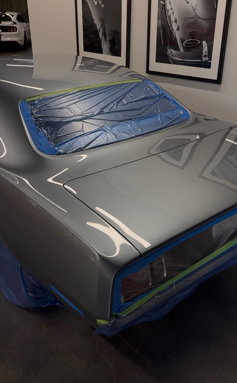 Windshield sunshade with blue fabric stretched across car hood in showroom with framed automotive photos on wall behind