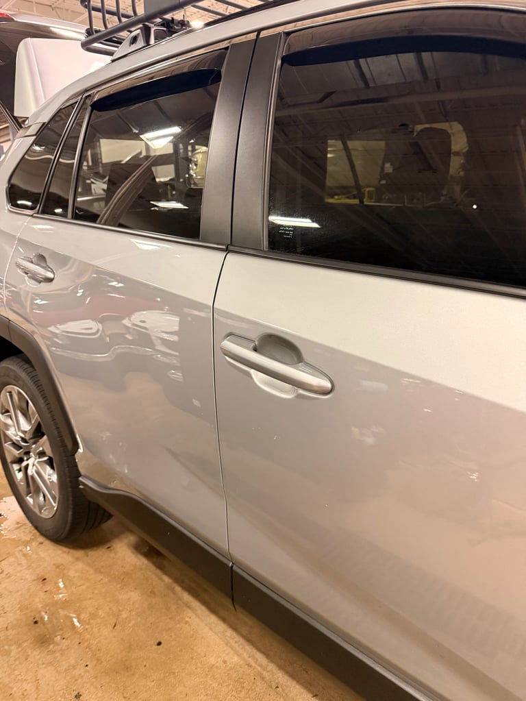 White SUV parked in garage showing side profile with tinted windows and roof rack