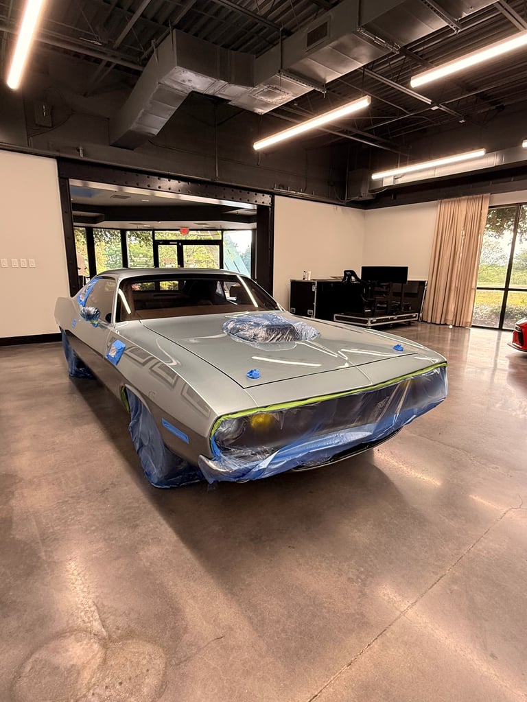Vintage car wrapped in blue plastic sheeting in a modern garage workshop with industrial ceiling lights