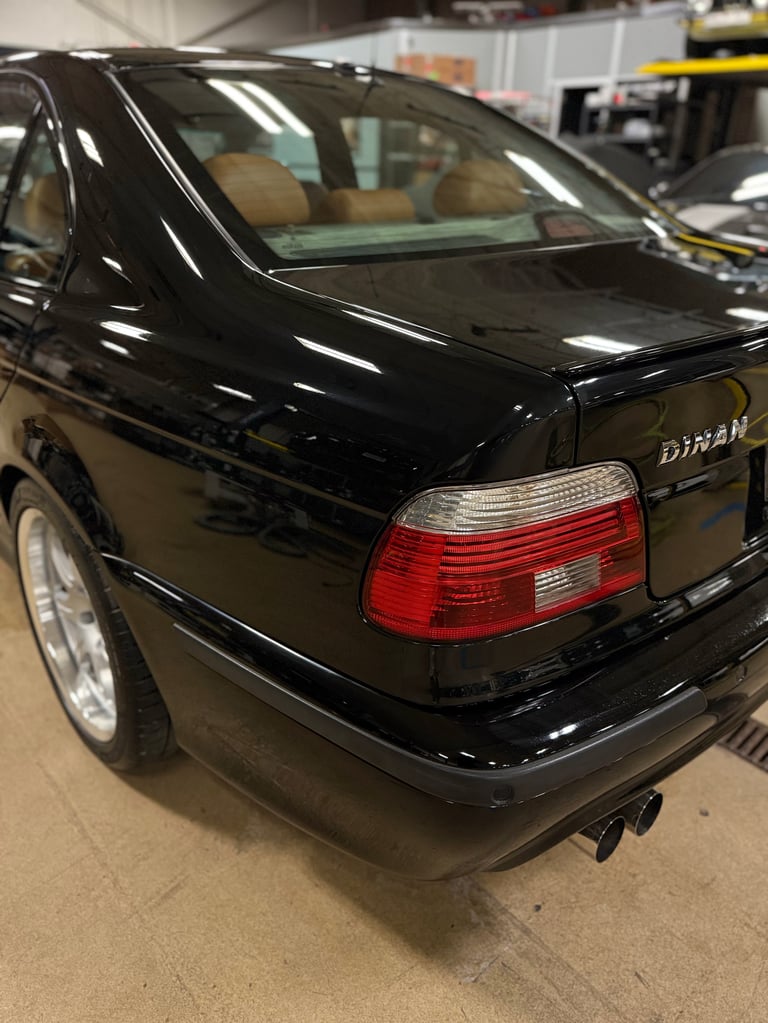 Black Nissan Datsun sedan with red taillights parked in an indoor garage or showroom