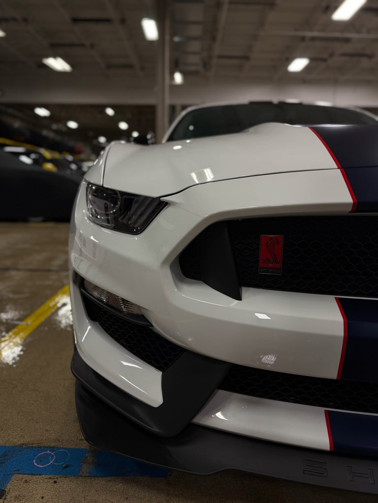 White Mustang with black and red racing stripes parked in indoor garage lot