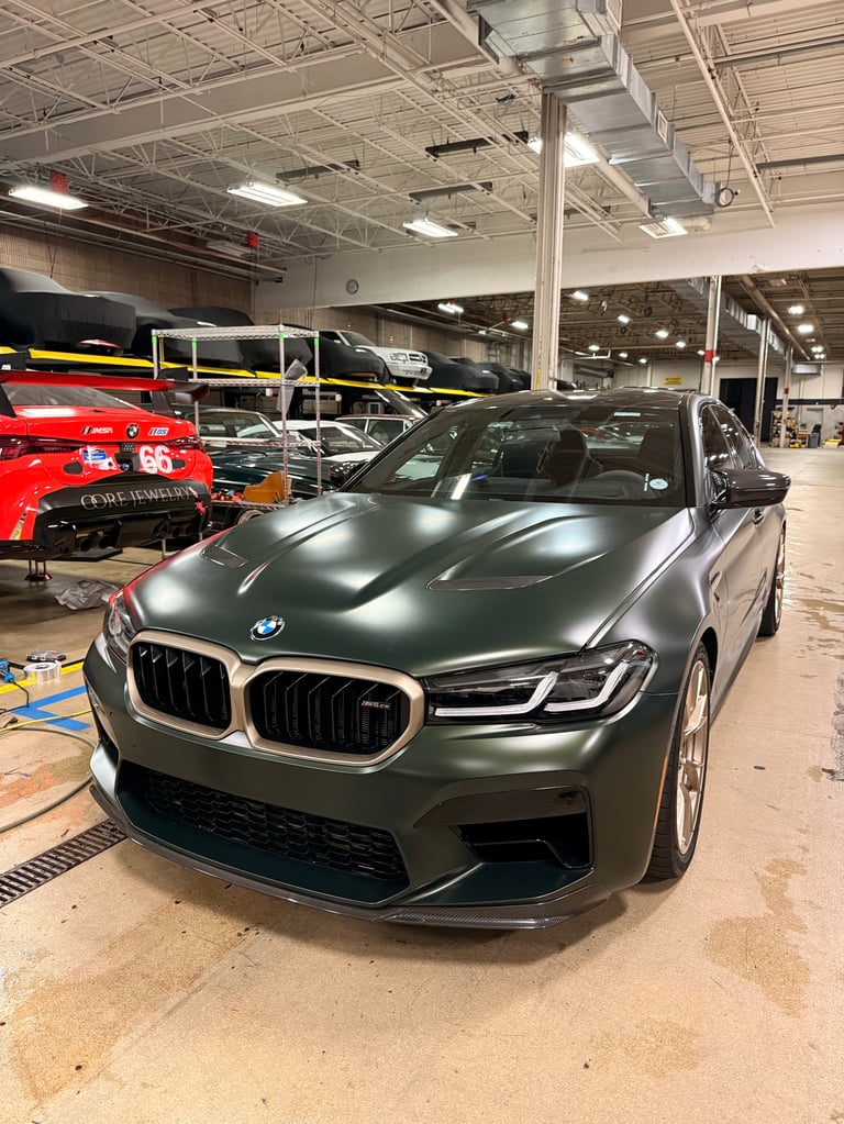 Gray BMW M340i sedan parked in a car warehouse with other vehicles visible in the background