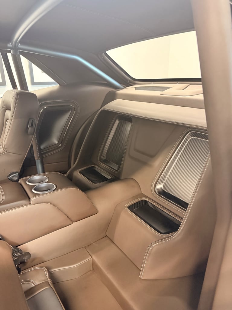 Luxury car interior with tan leather seats, cup holders, and panoramic sunroof viewed from drivers side door
