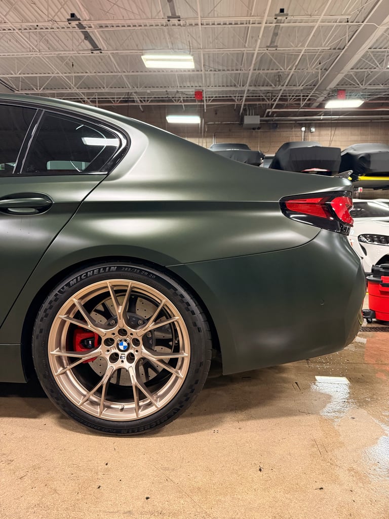 Gray BMW sports car with gold wheels and red brake calipers in an indoor garage facility