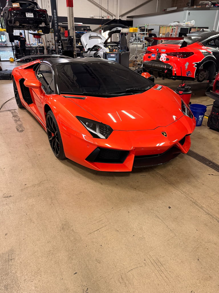 Red Lamborghini Aventador sports car with open door in an automotive workshop garage